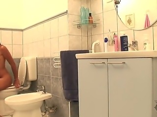 Beautiful young brunette Zafira has got filmed in the bathroom she is sitting on toilet nude and showing her shaved pussy pissing.