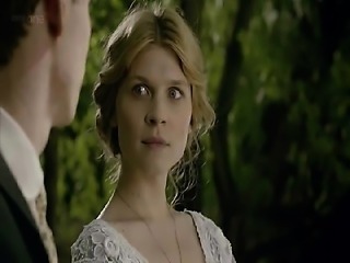 Clemence Poesy lying on her back in bed as a guy kisses her