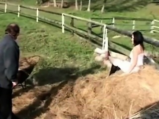 A guy is shifting hay and a teenage girl is watching him.