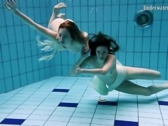 Two captivating young white girls under water in the pool